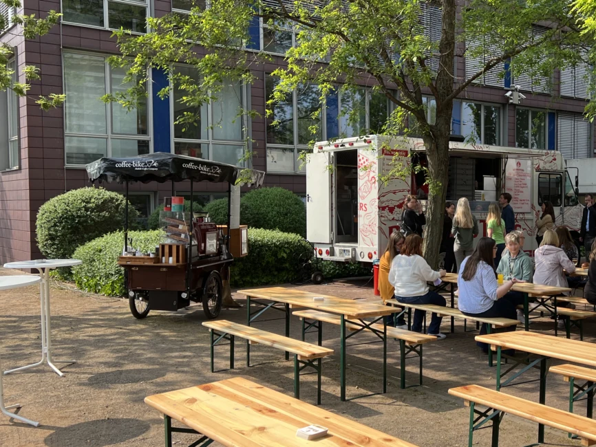 Mobile Kaffeebar steht draußen neben Bierbänken auf einem Sommerfest